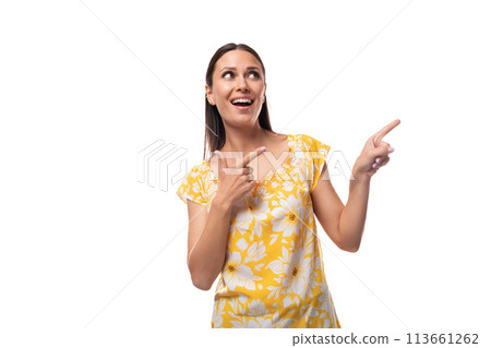Caucasian young woman with straight black hair dressed in a yellow sundress points with her hand to 113661262
