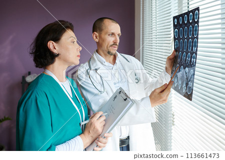 Neurosurgeon and medical nurse examining brain computer tomography scan 113661473