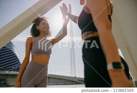 Happy female friends doing gesture of sport shake hand after exercising outside 113661505