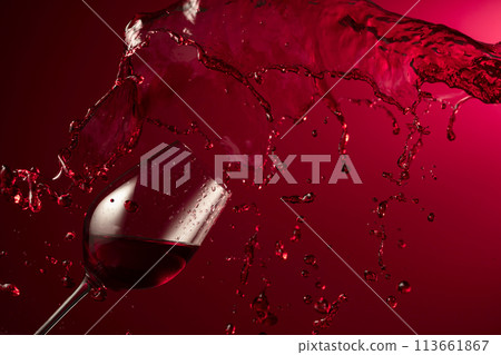 Glass and red wine splash on a dark red background. Glass and red wine splash on a dark red background. 113661867