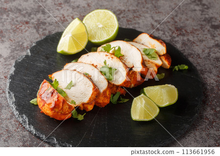 Sliced barbecue chipotle chicken breast served with lime and cilantro close-up on a slate plate. Horizontal Sliced barbecue chipotle chicken breast served with lime and cilantro close-up on a slate plate. Horizontal 113661956