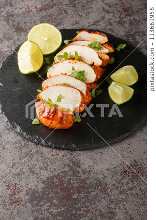 Delicious spicy chipotle chicken breast served with lime and cilantro close-up on a slate plate. Vertical 113661958
