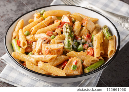Spicy pasta with honey glazed chicken, crisp-tender asparagus, bell peppers and sweet peas in a creamy chipotle Parmesan sauce closeup in the bowl. Horizontal Spicy pasta with honey glazed chicken, crisp-tender asparagus, bell peppers and sweet peas in a creamy chipotle Parmesan sauce closeup in the bowl. Horizontal 113661968