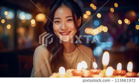 A woman smiling in front of a cake with lit candles 113661972