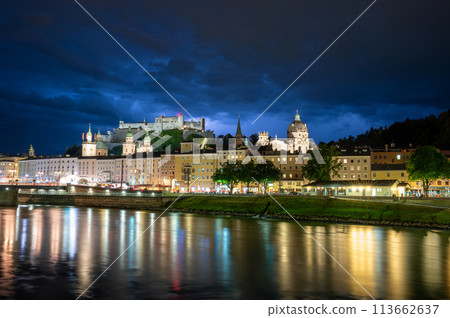 Salzburg, Austria, August 15, 2022. Fascinating night shot of the historic center overlooking the river. Behind, on the hill, the fort. Copy space. Dramatic sky, lightning near the fort. Salzburg, Austria, August 15, 2022. Fascinating night shot of the historic center overlooking the river. Behind, on the hill, the fort. Copy space. Dramatic sky, lightning near the fort. 113662637