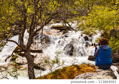 Tourist with camera at river, Norway Tourist with camera at river, Norway 113664081