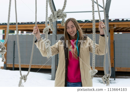 Woman Standing on Rope Swing in Snow Woman Standing on Rope Swing in Snow 113664183