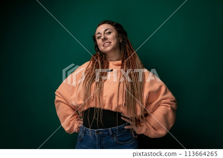 Woman With Dreadlocks Standing in Front of Green Wall 113664265