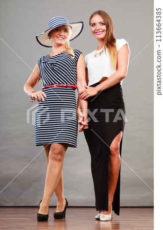 Two women wearing fashionable dresses. 113664385