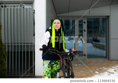 Woman Standing Next to Bike in Front of Building Woman Standing Next to Bike in Front of Building 113664530
