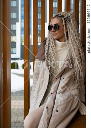 Woman With Long Blonde Hair Sitting on a Bench Woman With Long Blonde Hair Sitting on a Bench 113664542
