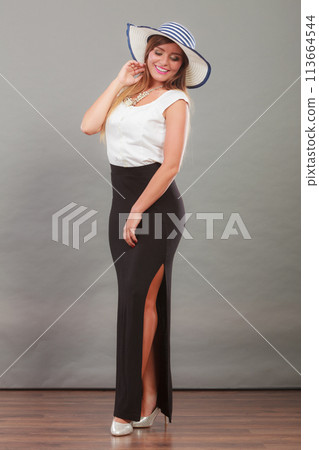 Woman wearing long black white dress and sun hat Woman wearing long black white dress and sun hat 113664544