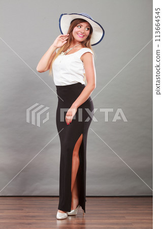 Woman wearing long black white dress and sun hat Woman wearing long black white dress and sun hat 113664545