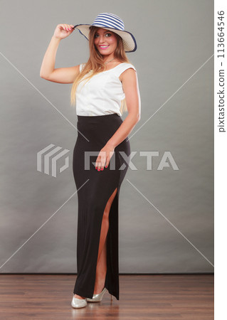 Woman wearing long black white dress and sun hat Woman wearing long black white dress and sun hat 113664546