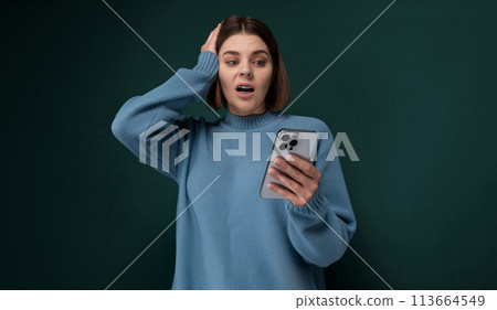 Woman in a Blue Sweater Holding a Cell Phone Woman in a Blue Sweater Holding a Cell Phone 113664549