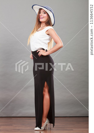 Woman wearing long black white dress and sun hat 113664552