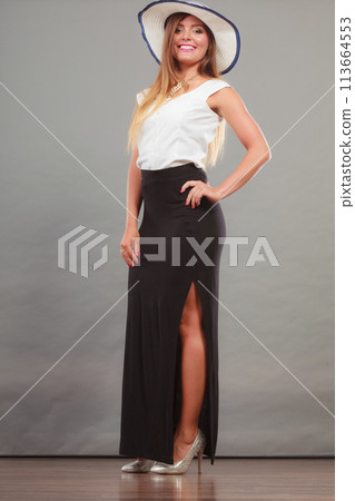 Woman wearing long black white dress and sun hat Woman wearing long black white dress and sun hat 113664553