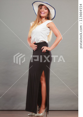 Woman wearing long black white dress and sun hat Woman wearing long black white dress and sun hat 113664554