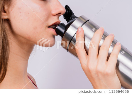 Closeup side view of sportive female after training who drinking fresh water from sport bottle Closeup side view of sportive female after training who drinking fresh water from sport bottle 113664666