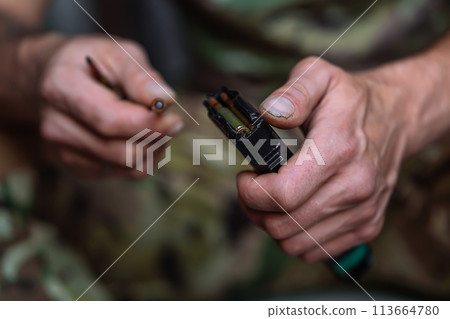 Close-up shot of hands of Ukrainian military man loads the assault rifle magazine with cartridges 113664780