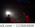 Rock band vocalist silhouette with the guitar singing to microphone with the hand raised up in red lights 113664806