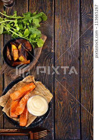 pieces of battered fish on a plate with baked potato on a wooden table with space pieces of battered fish on a plate with baked potato on a wooden table with space 113665267