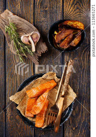 pieces of battered fish on a plate with baked potato on a wooden table with space 113665271