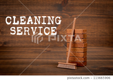 Cleaning Service Concept. Miniature broom on wooden texture background Cleaning Service Concept. Miniature broom on wooden texture background 113665906