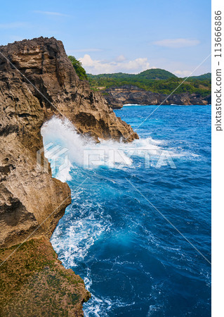 Cinematic aerial landscape shots of the beautiful island of Nusa Penida. Huge cliffs by the shoreline and hidden dream beaches with clear water and foaming wave. 113666886