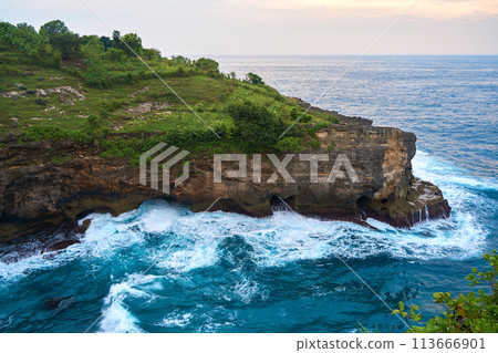 Cinematic aerial landscape shots of the beautiful island of Nusa Penida. Huge cliffs by the shoreline and hidden dream beaches with clear water and foaming wave. 113666901