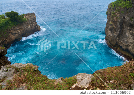Cinematic aerial landscape shots of the beautiful island of Nusa Penida. Huge cliffs by the shoreline and hidden dream beaches with clear water and foaming wave. 113666902