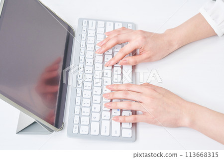 A woman's hands typing on a keyboard 113668315