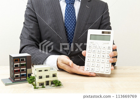 Businessman holding a calculator and a house model 113669769