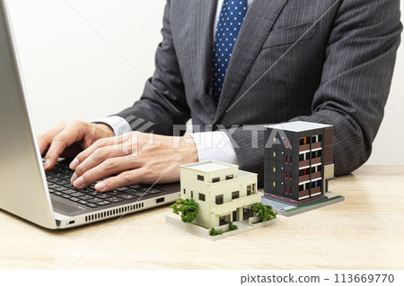 一位商人在電腦和房屋模型上工作 113669770