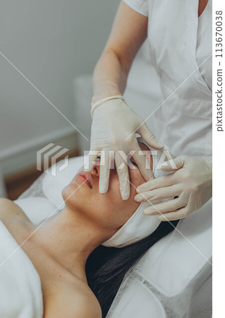 girl at a cosmetologist's office doing skin cleansing girl at a cosmetologist's office doing skin cleansing 113670038