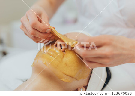 A girl at a cosmetologist does cosmetic procedures. Alginate mask 113670056