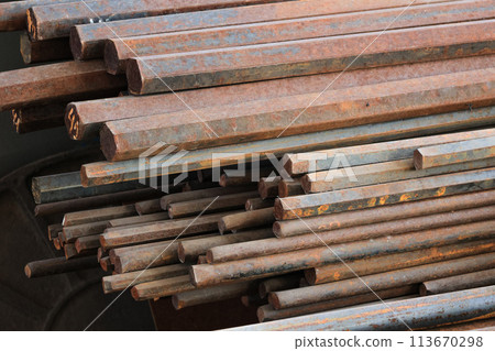 A pile of rusty metal rods. The rods are stacked on top of each other and are all different sizes 113670298