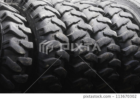 A close up of a tire with a black rim. The tire is black and has a lot of tread 113670302