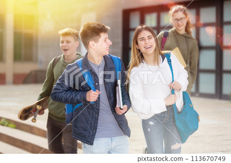 Smiling teenagers walking outside after lessons Smiling teenagers walking outside after lessons 113670749