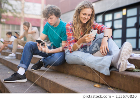 Teenagers with smartphones sitting on stairs Teenagers with smartphones sitting on stairs 113670820