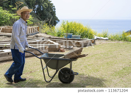 A man carrying lumber in a handcart A man carrying lumber in a handcart 113671204
