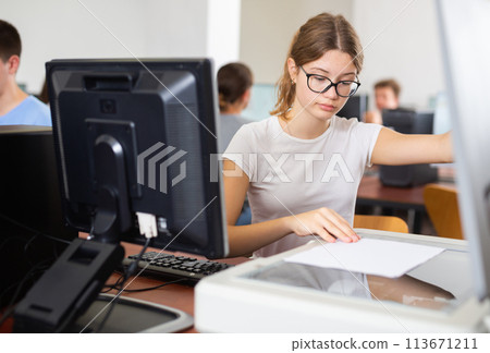 Smart female teenager learning computer science while she is using a PC and scanner in the computer classroom 113671211