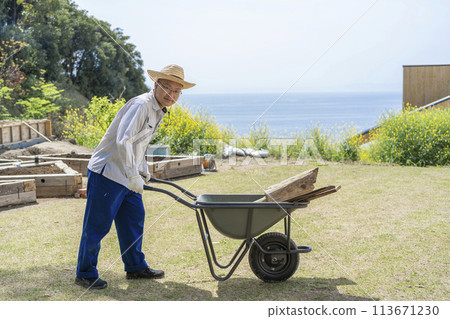 A man carrying lumber in a handcart 113671230
