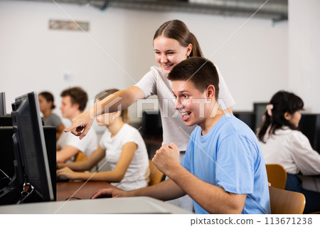 Positive toung boy and girl playing videogame in computer class Positive toung boy and girl playing videogame in computer class 113671238