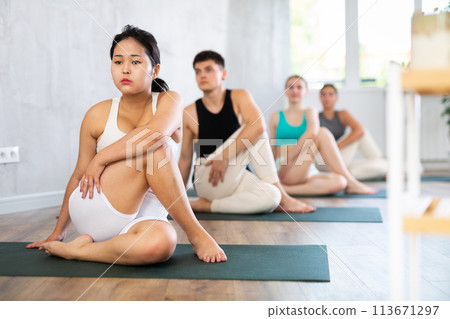 Young woman practicing lord of the fishes pose of yoga in light fitness room Young woman practicing lord of the fishes pose of yoga in light fitness room 113671297