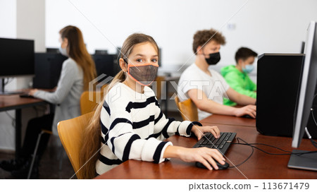 Young girl in mask using computer during lesson 113671479