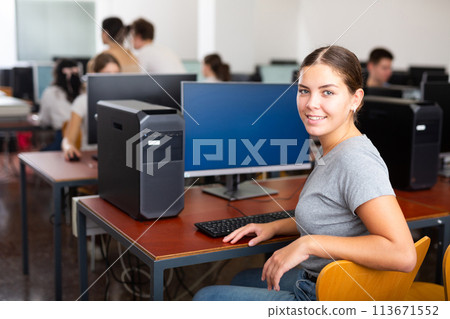 Positive female student smiling, using PC and studying computer science in the classroom 113671552