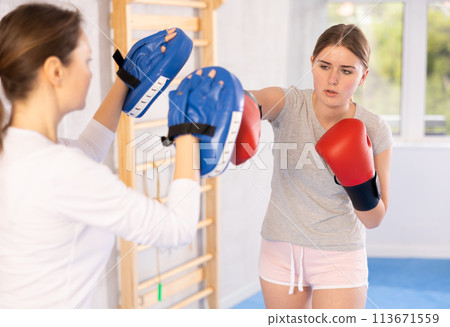 Teen girl in punch mitts boxing Teen girl in punch mitts boxing 113671559