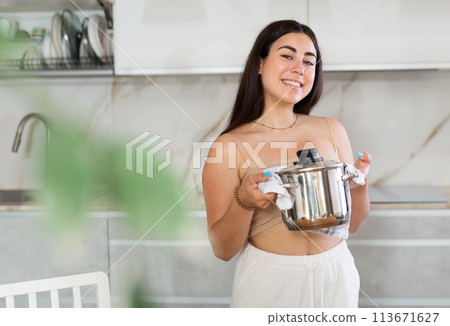 Young woman posing with saucepan in kitchen at home 113671627