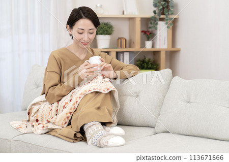 Woman relaxing in the living room, warming up, poor circulation 113671866